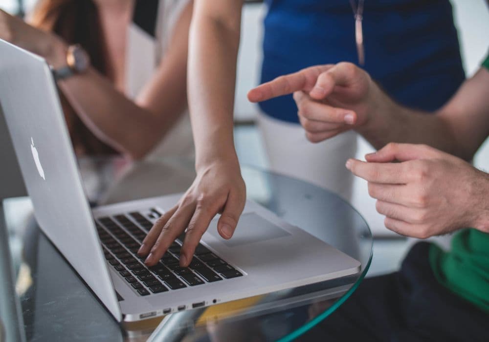 People collaborating at laptop, pointing at screen during discussion